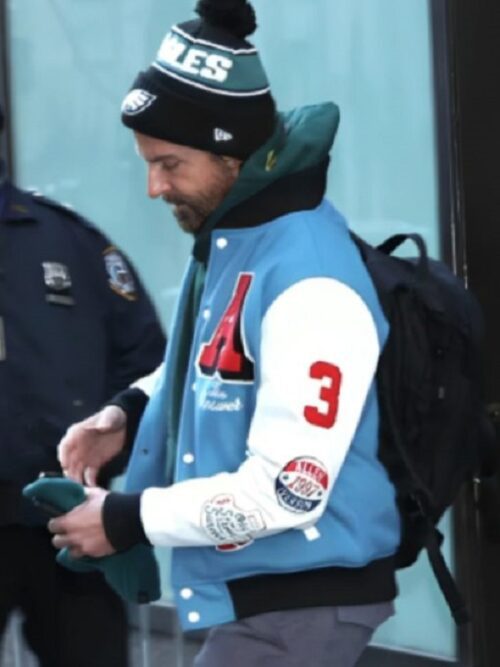Bradley Cooper sports a basketball jacket and hat, capturing the essence of NYC basketball varsity style.
