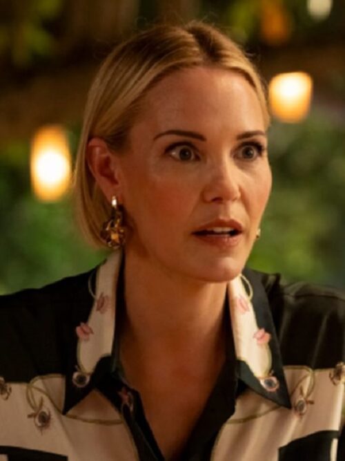 Leslie Bibb is seen wearing The White Lotus S3 Leslie Bibb Printed Silk-Twill Shirt, featuring an intricate floral design on a luxurious silk-twill fabric. The shirt’s elegant contrast of black and cream tones, adorned with delicate pink and gold details, exudes a sophisticated yet effortlessly chic style.
