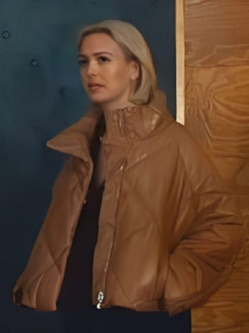 Theresa Frostad Eggesbø, in a brown jacket, stands confidently in front of a door, embodying her character from the TV series Ragnarok.