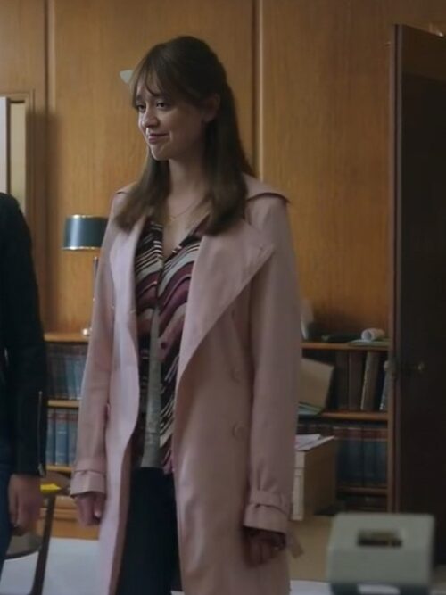 Aimee Lou Wood is seen wearing the Toxic Town Aimee Lou Wood Pink Coat, a stylish and elegant pastel pink trench coat. The coat’s soft hue and tailored fit add a sophisticated touch to her outfit, which includes a patterned blouse and dark pants. Set in a classic office environment, this look blends vintage charm with modern fashion.